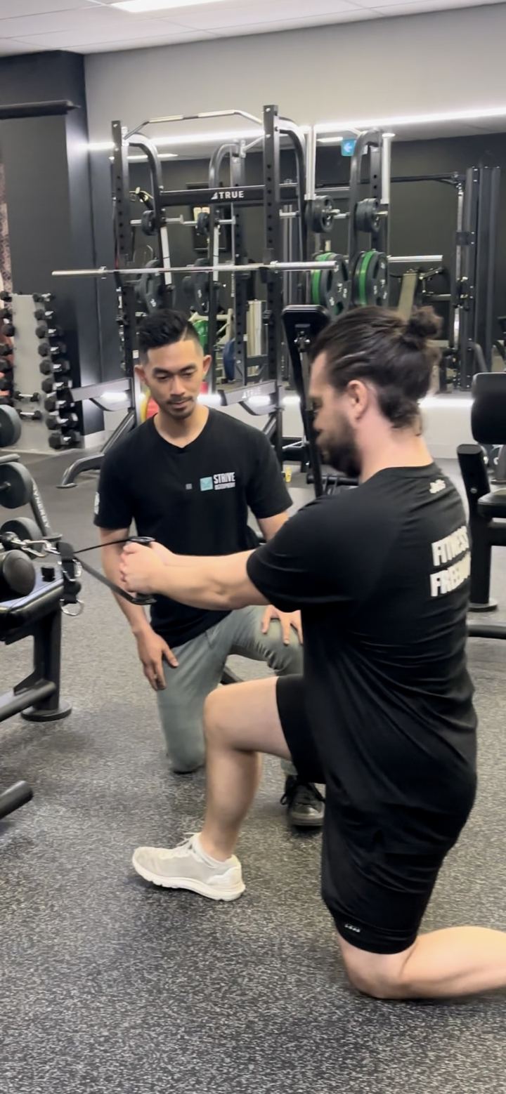 Joshua Milanes supervising a client's gym training at Strive Osteopathy